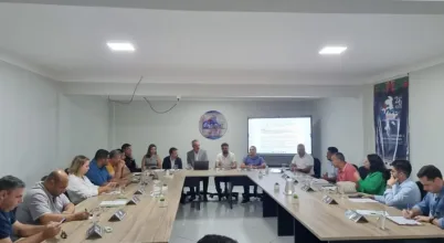 Equipe reunida com produtores e parceiros em mesa de trabalho